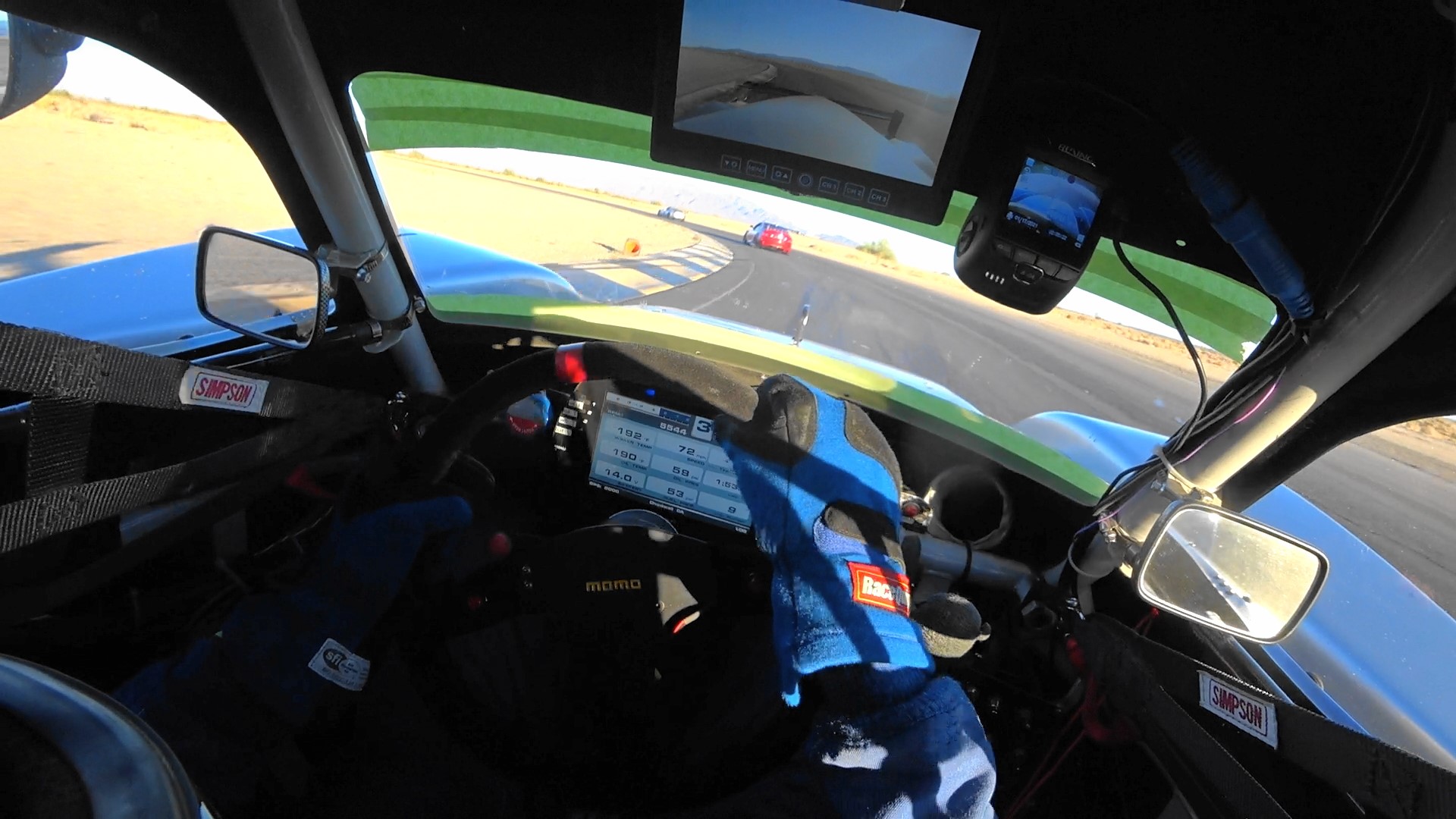 A photo of a driver in the interior of a race car driving on a track.